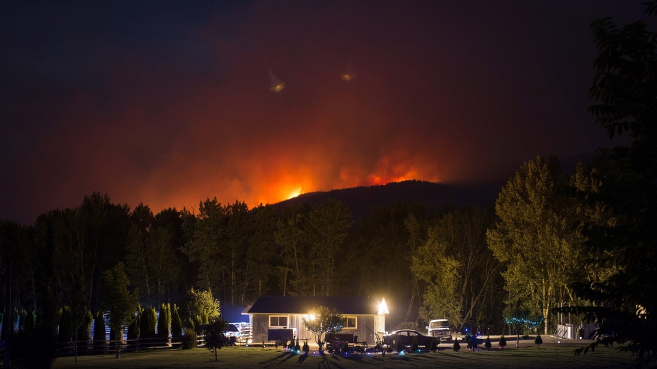 A wildfire burns on a mountain behind a home in Cache Creek, B.C., in the early morning hours of Saturday July 8, 2017