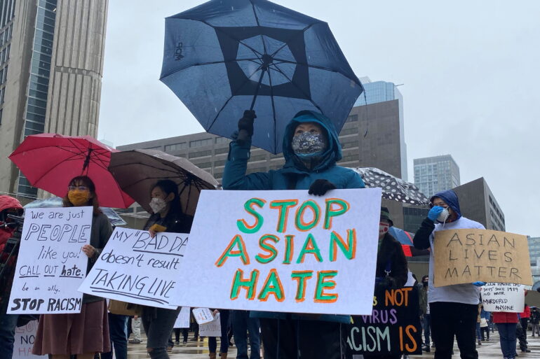 People hold placards as they gather to protest against anti-Asian hate crimes, racism and vandalism, outside City Hall in Toronto, Ontario, Canada, March 28, 2021.