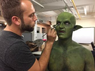 Shaun doing detailed work on a model dressed as a green monster