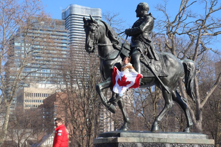 Protester present at Queens Park waving the Canadian Flag