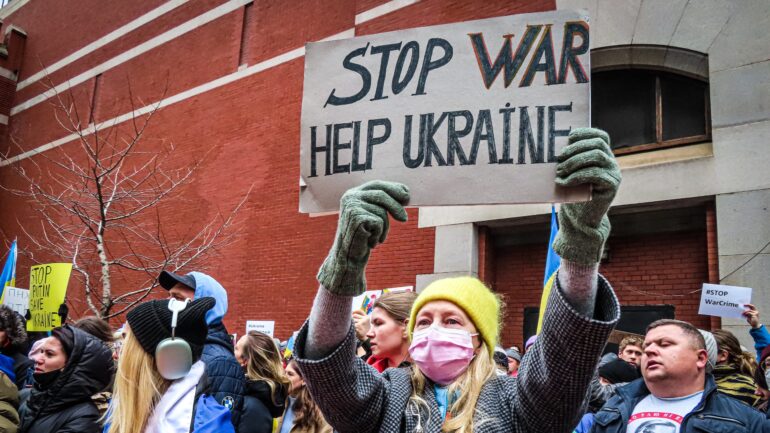 People seen protesting. A woman holds poster reading: STOP WAR, HELP UKRAINE