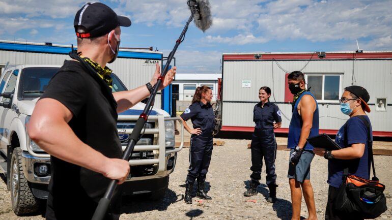 Director Raoul Bhatt, second from right, checks the scene before filming on the set of the gritty oil patch drama Pipe Nation in Sundre, Alta., in 2020.