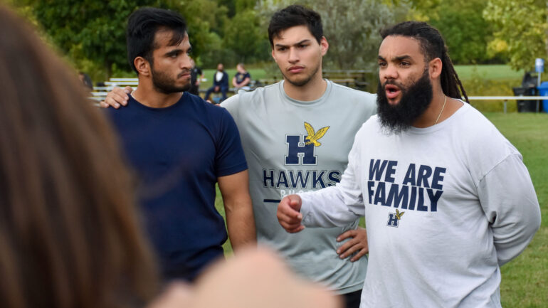 Hawk Wings Rajat Raj and Juan Camargo listening to assistant coach Andre Rose-Green in team huddle during Wednesday practice ahead of Today's game versus Durham