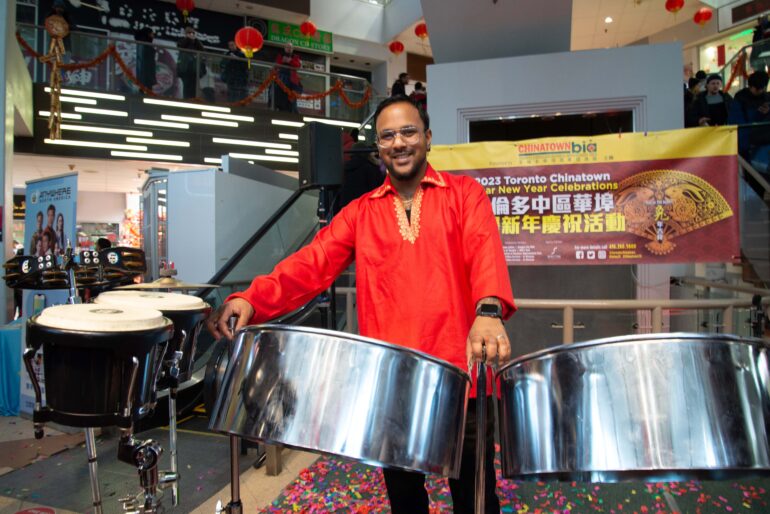 Aaron Seunarine talks to the audience in front of a steelpan set after his performance.