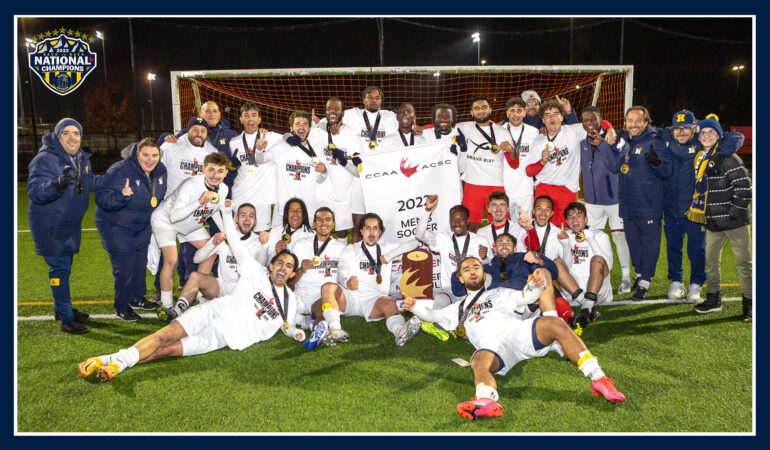 2022-23 Humber Men's Soccer team posing with their National Championship Banner