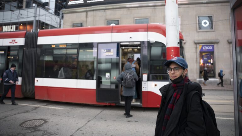 August Pantitlán Puranauth, a Toronto Metropolitan University student and TTCriders organizer, stands at a bus stop near Dundas Square.