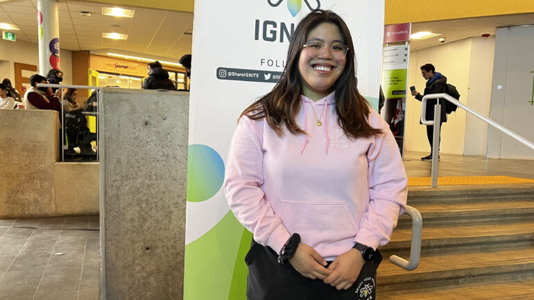 Humber IGNITE representative, Anne Ravina wearing an IGNITE branded pink sweater on Pink Shirt Day