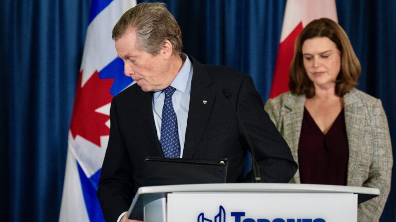 John Tory walks away from the Toronto city hall podium, as deputy mayor Jennifer McKelvie looks on Feb. 17, 2023. Tory began to hand over his mayoral powers at Toronto City Hall on Friday, as he makes a scandal-plagued exit from office.