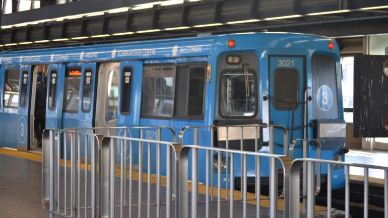 A blue train sits in a transit station