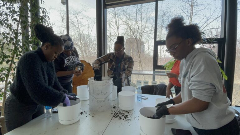 Female students at table putting soil into planters