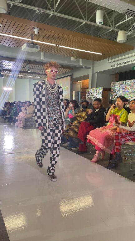 a fashion student walks the runway in a checkered suit