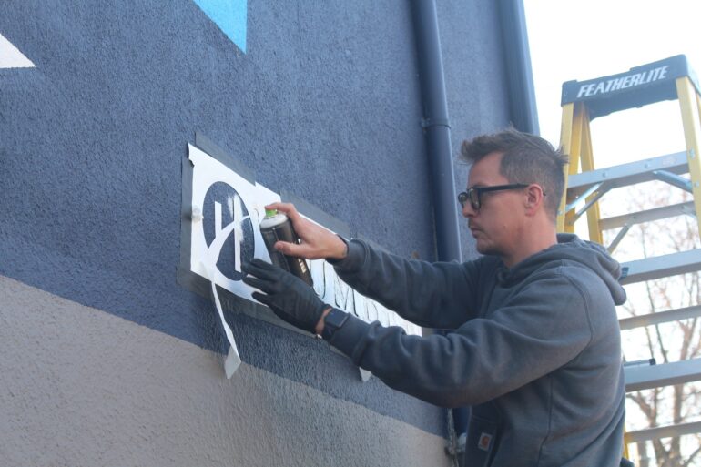 Artist Ben Johnston putting the finishing touches on the Bring It mural.