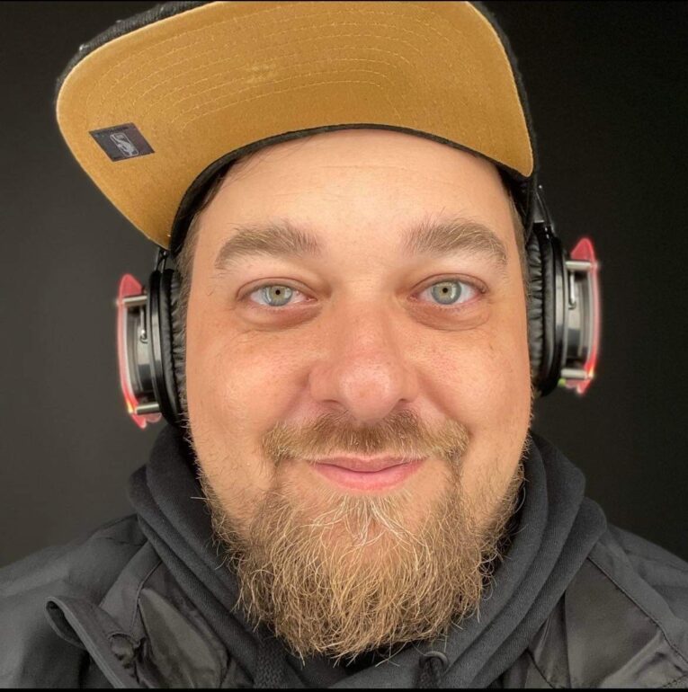A selfie of a  man wearing a yellow cap with his headphones.