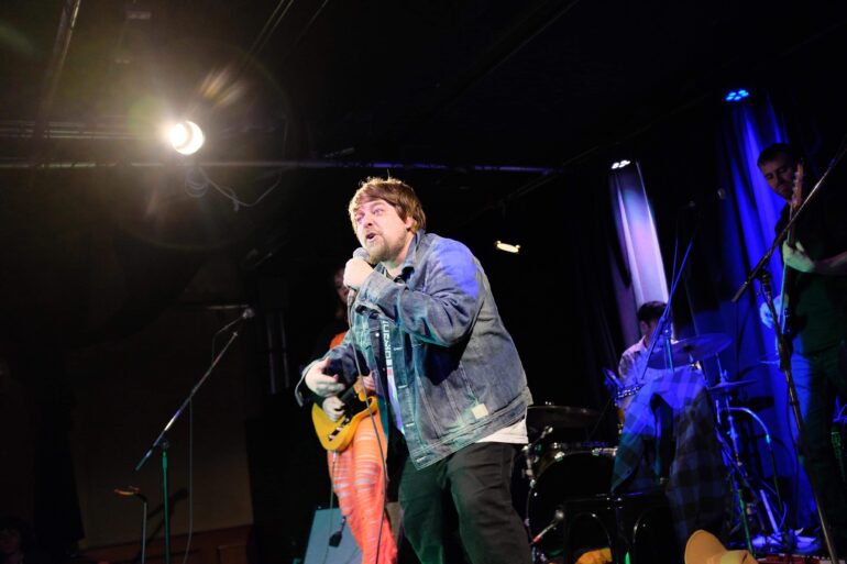 A man holding a mic and performing on the stage.