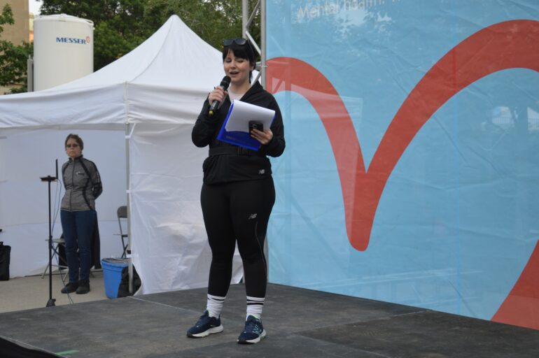 Ruby Carr speaking on stage to Run for Women runners before the race starts at the Women's College Hospital.