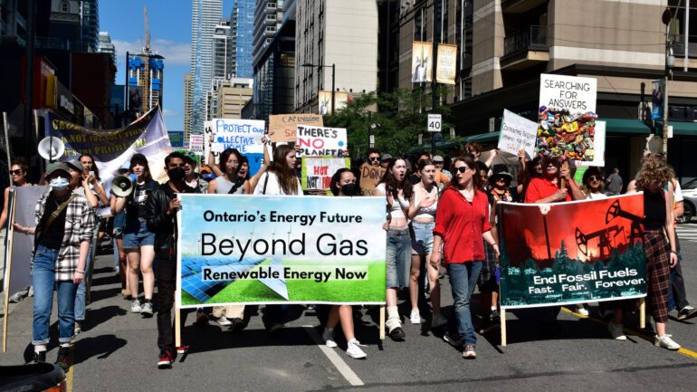 People with signs march in downtown Toronto for the Global March to End Fossil Fuels on Saturday, 16