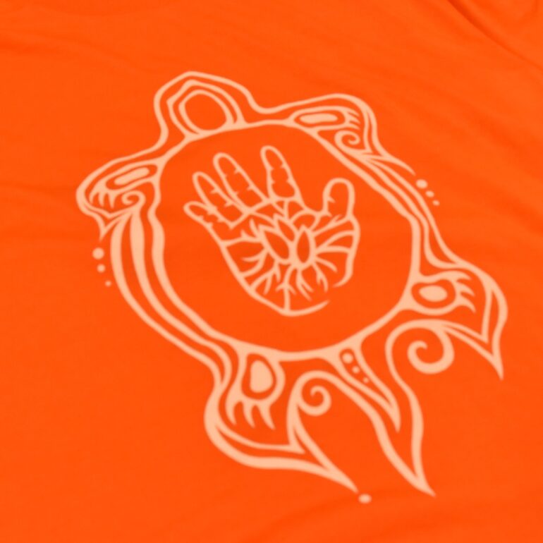 Close-up of the turtle and hand design on the orange T-shirt.