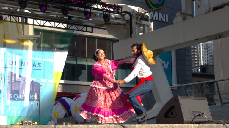 Two dancers from the Mexican dance group "Kami Torres y Su Grupo" performing on stage at Yonge Dundas Square.
