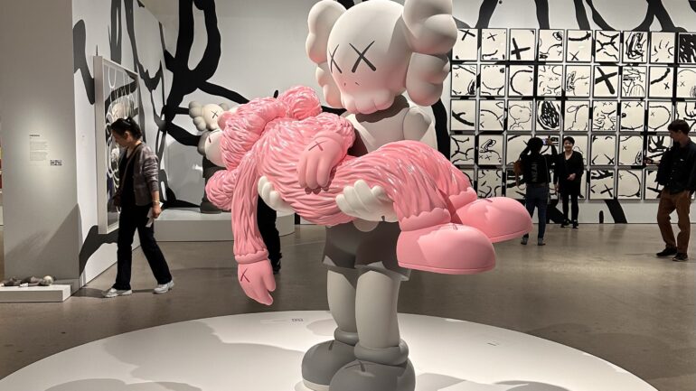 More than five people can be seen gathering around the KAWS GONE statues.