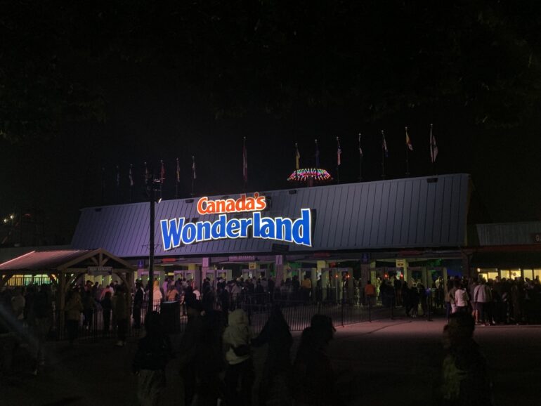 In the center of the image is a bright sign that says "Canada&squot;s Wonderland." In the lower one-third of the image are people lining up to get into the park.