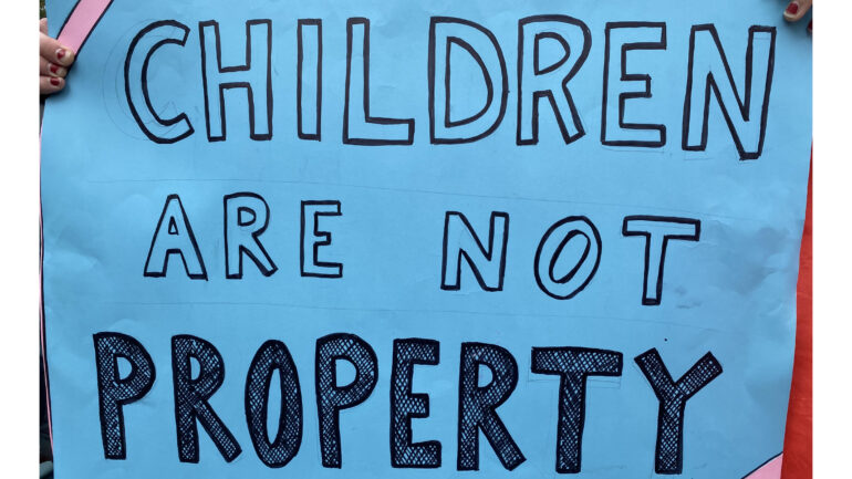 A sign held by counter protesters reading "Children are not property" in all capitals