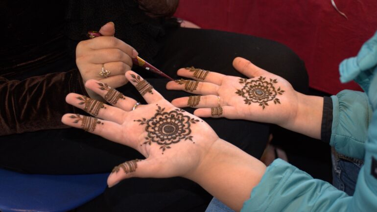 A person getting henna designs done at the henna booth.
