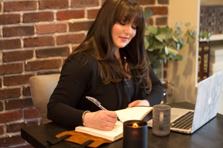 An image of a female with brown hair writing notes.