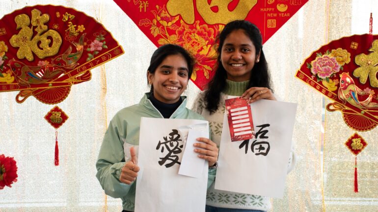 International students Kashish Sethi (left) and Sindhu Appikatla (right) show off their work from the calligraphy and New Year's Resolution card-making stations of the Lunar New Year Event at the Lakeshore campus on Feb. 8.