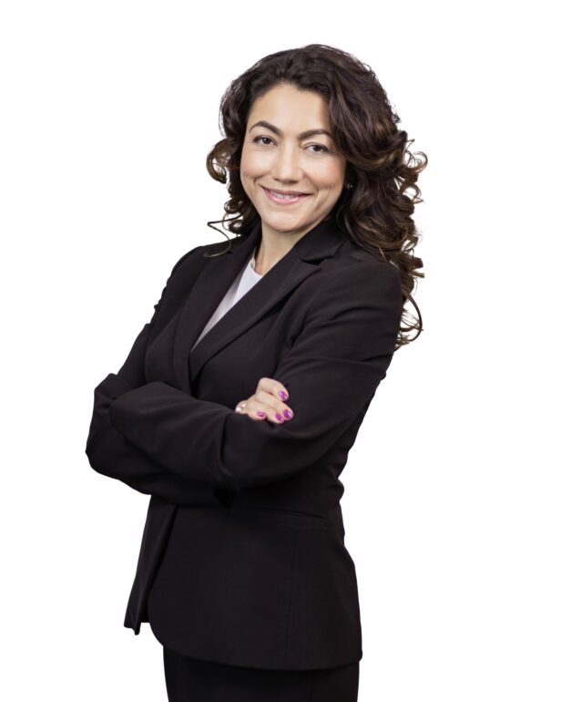 A person with long, curly hair wearing a skirt suit in front of a white background.