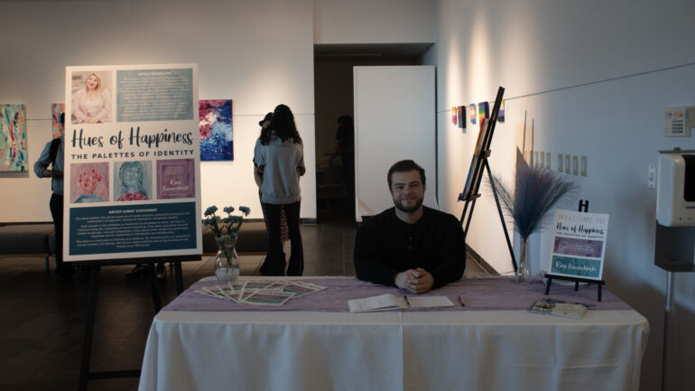 A picture of Nicholas Baschiera sitting at the welcome table of the art gala.