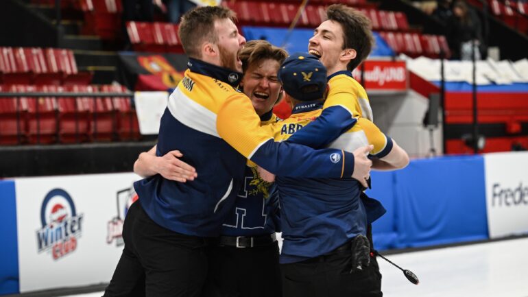 The Hawks men's curling team embrace after the championship clinching shot.