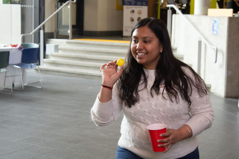 girl holding a yellow ball and a cup