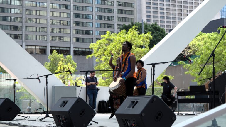 Members of The Ngoma Ensemble are playing the drums for a performance in Toronto's Newcomer Day event.