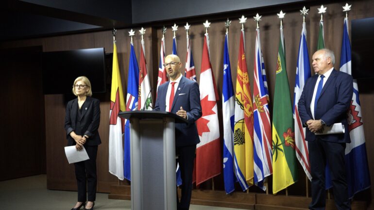 Laurence Applebaum, Jeff Calderwood, and Louise Parry standing at the front of the press conference in Ottawa.