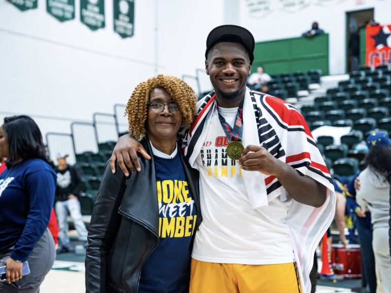 Jamani Barrett with a family member after winning the 2023 OCAA Championship wearing his medal.