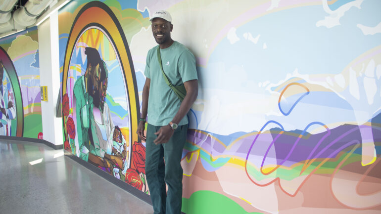 Artist Phillip Saunders stands next to his mural.