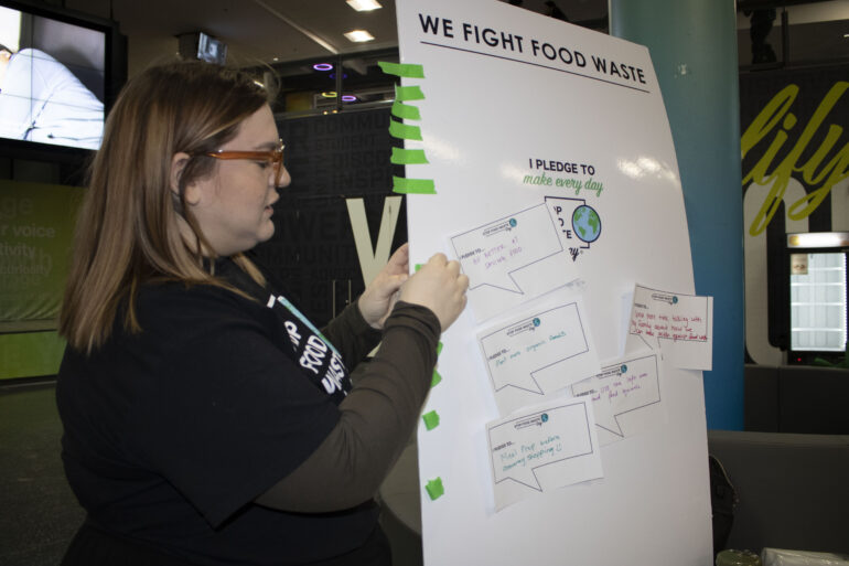 Alessa Crispo from Humber's Student Life and Campus Experience posts pledges on the We Fight Food Waste pledge board.