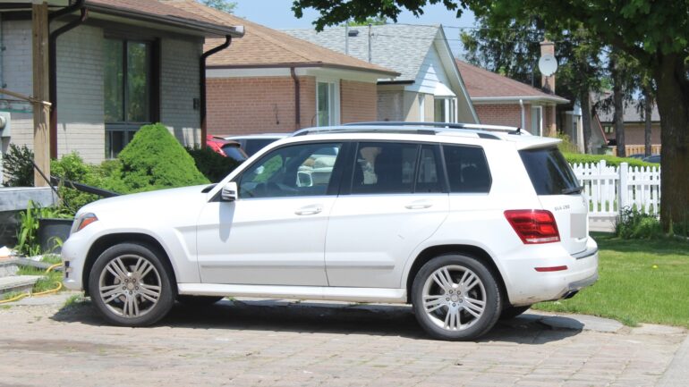 A white SUV parked in the driveway of a home in Etobicoke in the afternoon.
