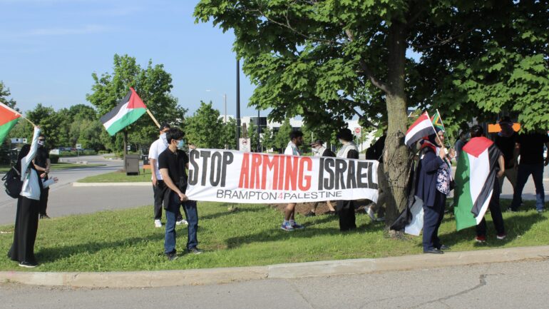 Protesters holding Palestinian flags and banner that says "Stop arming Israel" at the protest site in Brampton outside the Banquet Hall where Miller&squot;s fundraiser was being held on June 3.